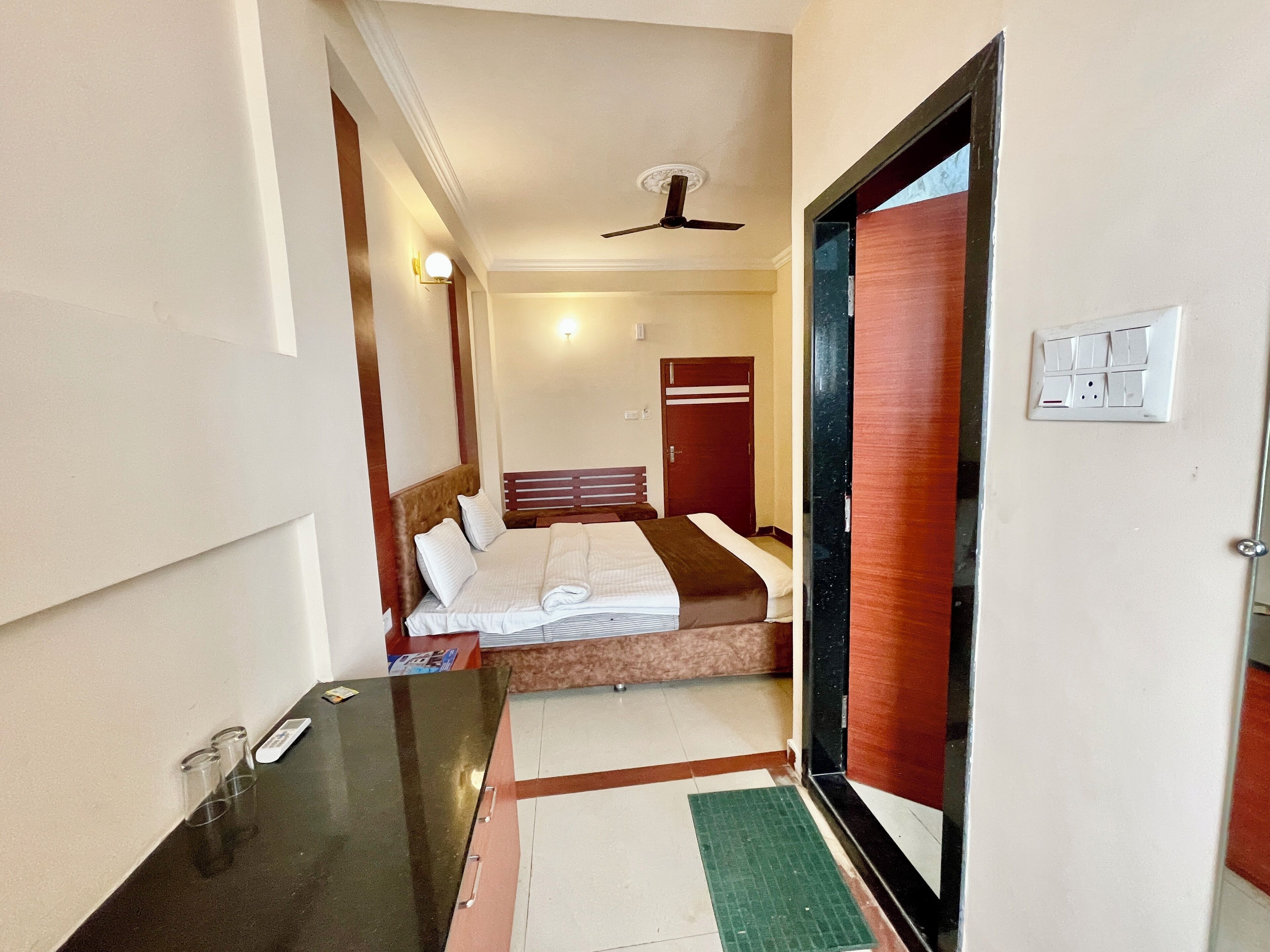A hotel room with a bed, bedside table, and a ceiling fan.