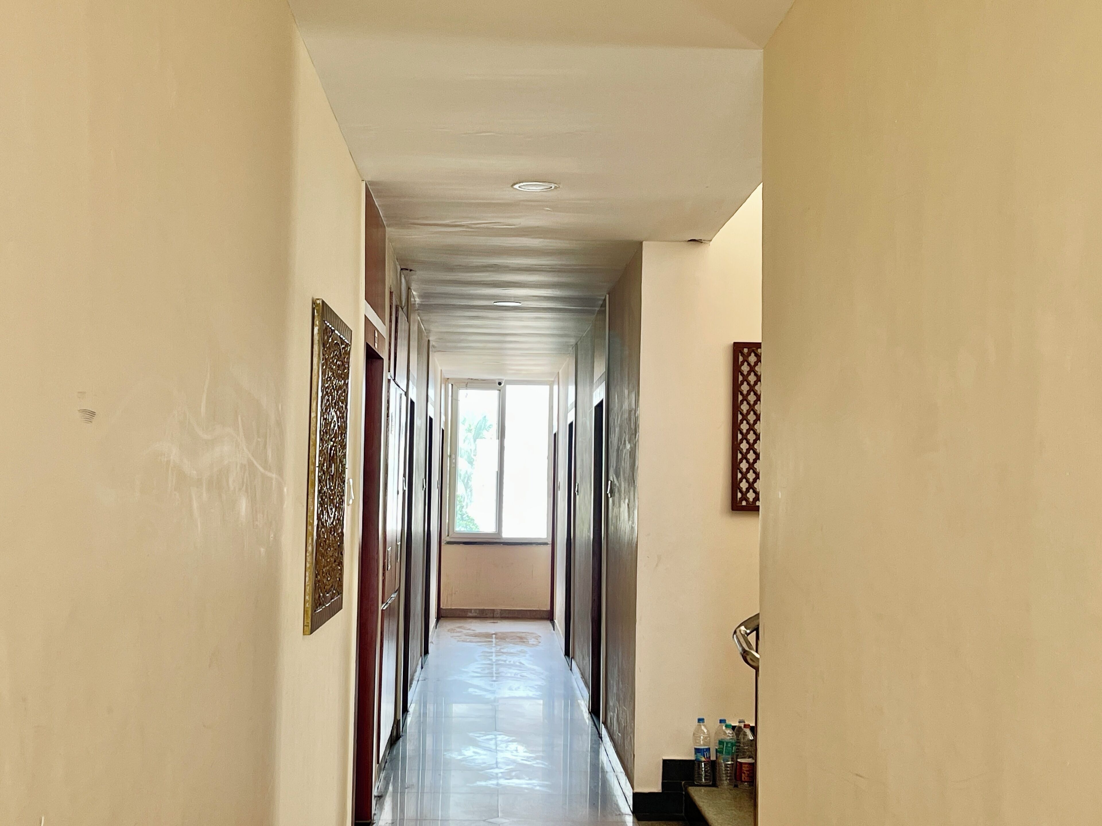 A long, narrow hallway with a tiled floor, leading to a bright room with a window.