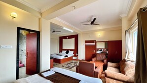 A hotel room with a bed, a desk, a chair, a mirror, and a ceiling fan. - Hotel Subham Beach Inn - near Sea Beach (Puri)