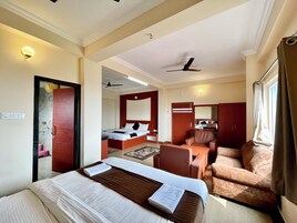 Une chambre d’hôtel équipée d’un lit, d’un bureau, d’une chaise, d’un miroir et d’un ventilateur de plafond.