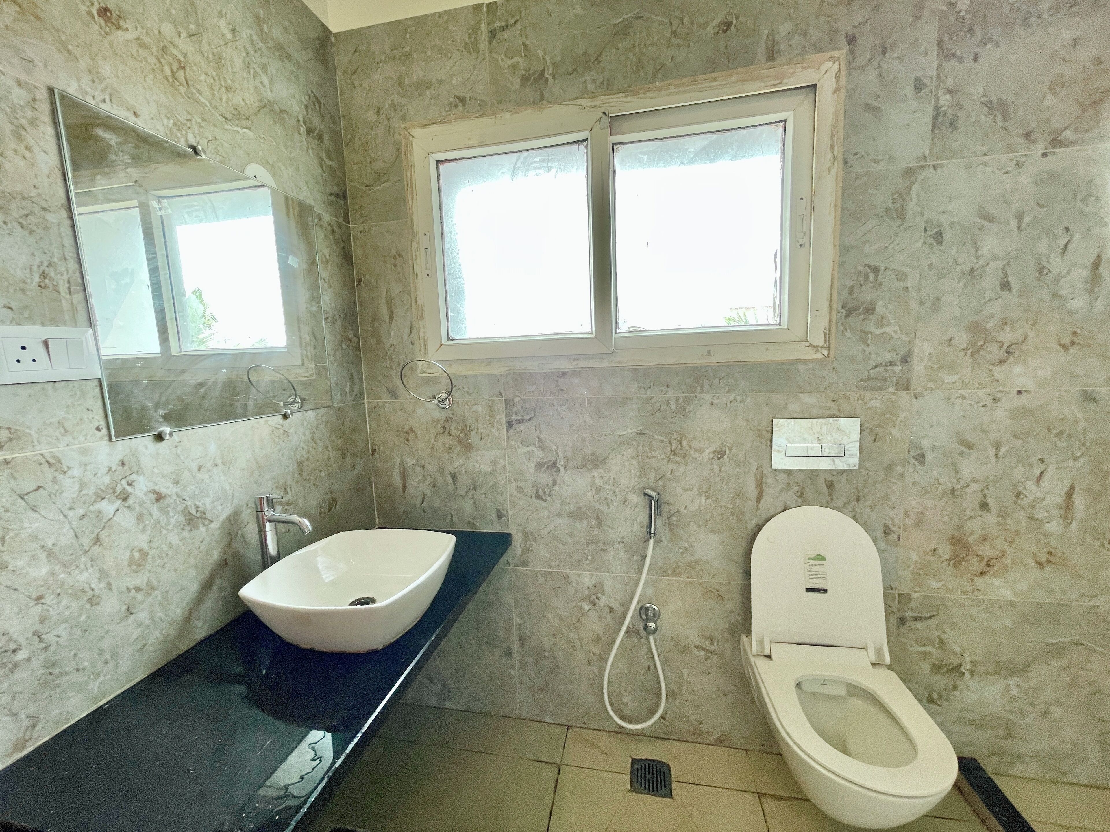 A bathroom with a white sink, a toilet, a shower, and a window above the toilet.