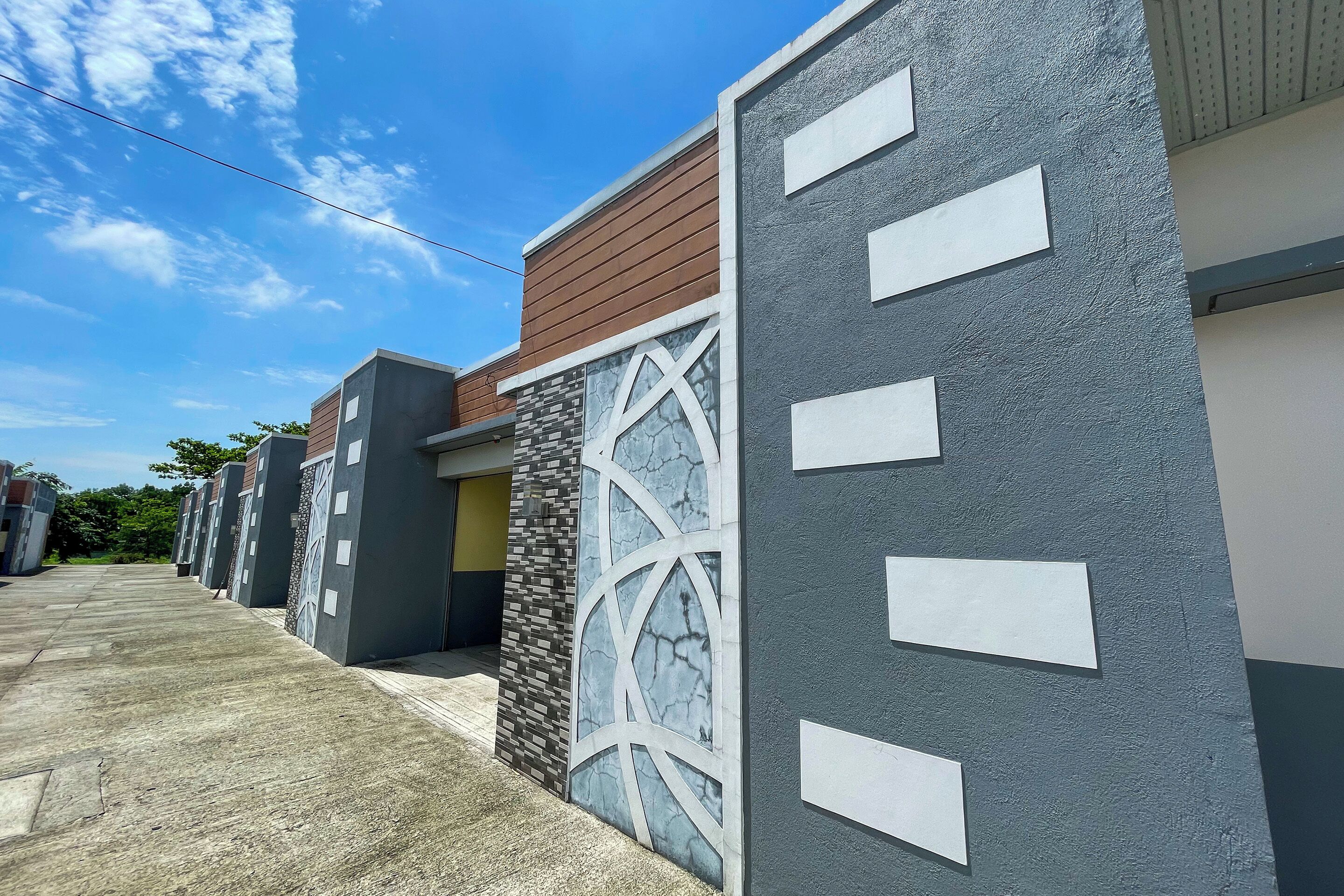 A modern building with a mix of wood and stone facades, a concrete ground floor, and a clear sky.