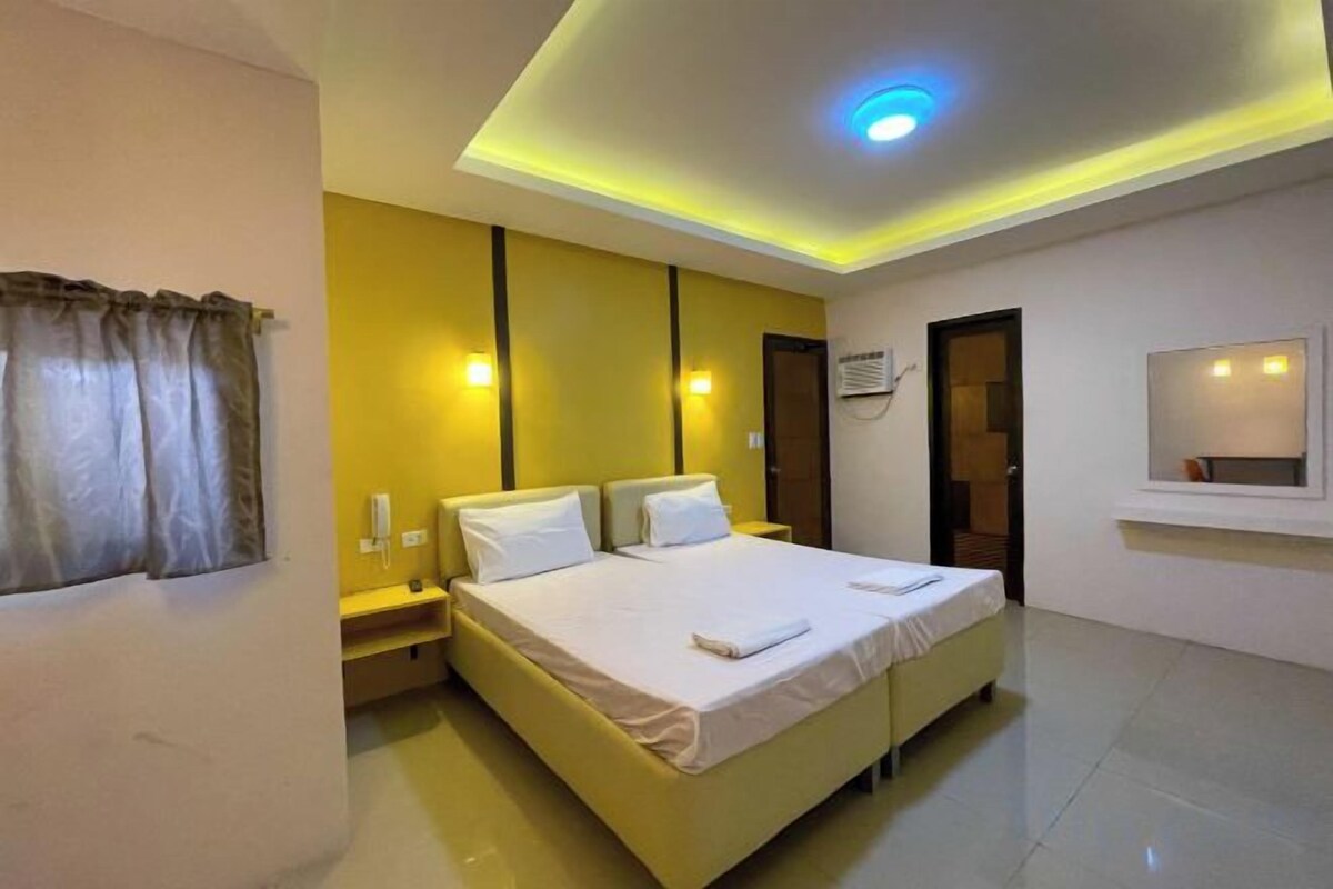 A hotel room with a bed, bedside tables, a mirror, and a ceiling light.