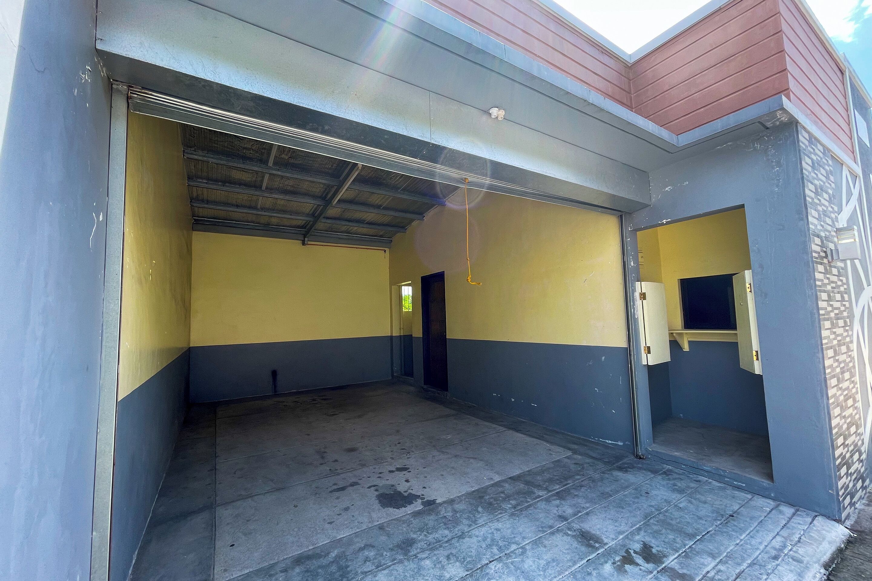 A covered parking area with a metal roof and yellow and gray walls.
