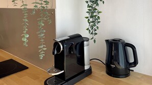 Un coin cuisine équipé d’une machine à café, d’une bouilloire et agrémenté de plantes suspendues.