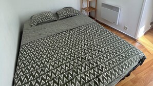 Une chambre à coucher avec un lit, une table de chevet avec une lampe, un radiateur et un miroir au mur.