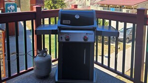 A Weber Spirit portable grill on a balcony with a propane tank, overlooking a mountain and a residential area. - Ski In/Out - Hot tub - Fireplace - BBQ (Panorama)