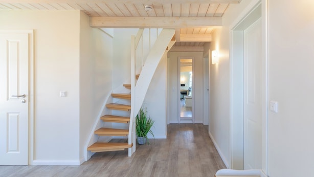Ein Flur mit einer Holztreppe, einem Blumentopf und einer Bank.