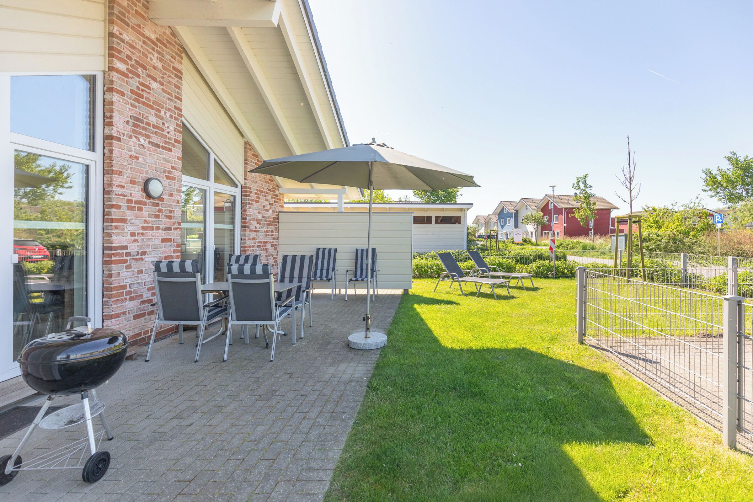 En terrasse med udendørs møbler, grill og et overdækket område med parasol.