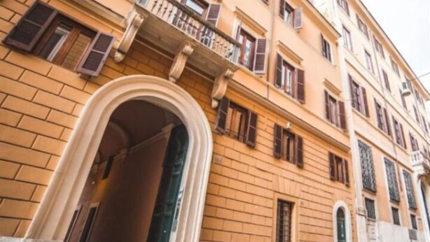 A multi-story building with a classic architectural style, featuring a prominent entrance with an archway and a balcony on the second floor. - TREVI PORTRAIT (Rome)