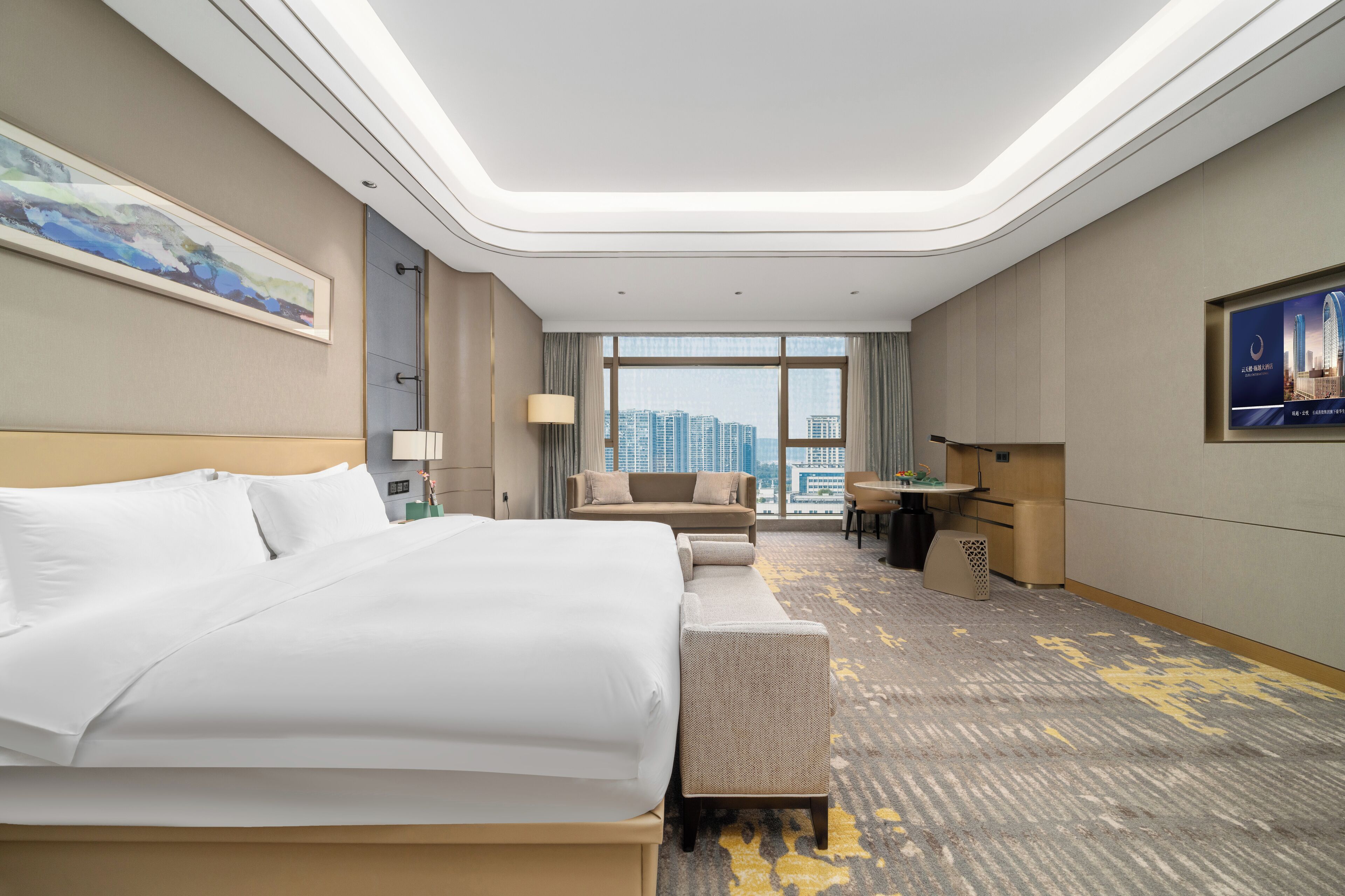 Ett hotellrum med en stor säng, en soffa, ett skrivbord och utsikt över stadsbilden.