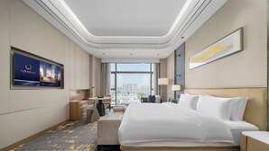 Une chambre d’hôtel avec un grand lit, un bureau, une chaise, une télévision et une vue sur la ville.