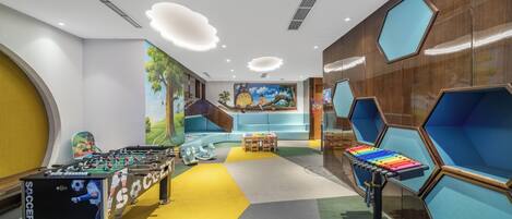 A brightly lit indoor space with a foosball table, a colorful xylophone, and a mural on the wall.