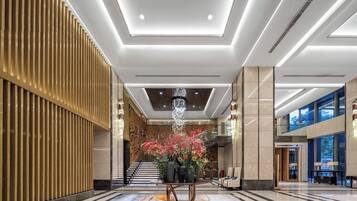 A modern lobby with a central floral arrangement, a staircase, and a seating area.