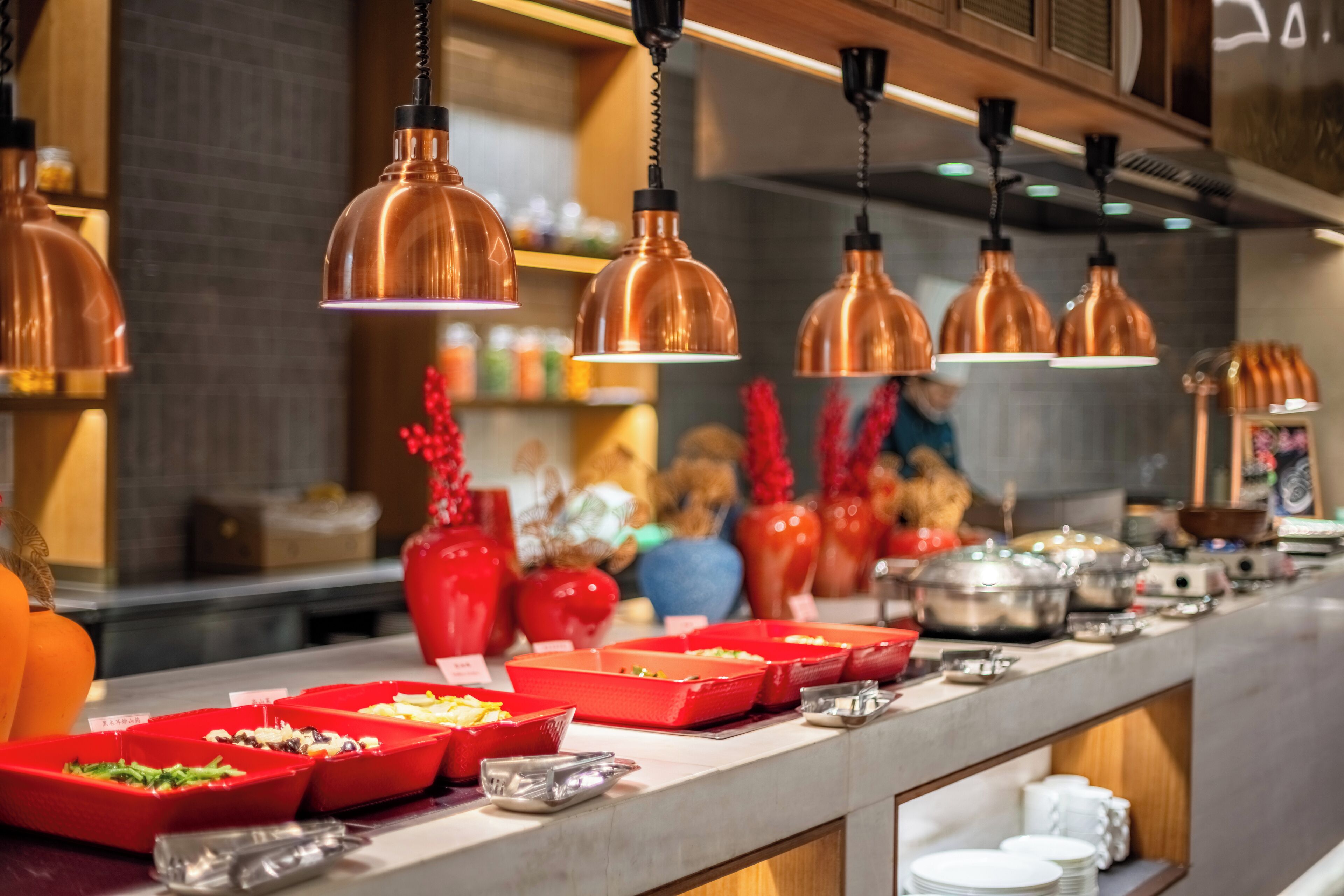 Disposição de buffet com vários recipientes de comida e utensílios de servir.