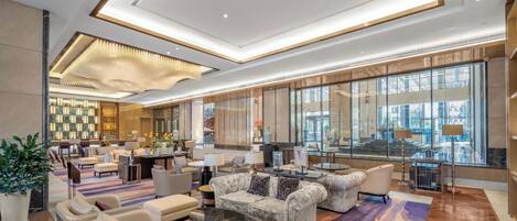 Un vestíbulo espacioso con muebles modernos, pared a cuadros y amplias ventanas con vistas.