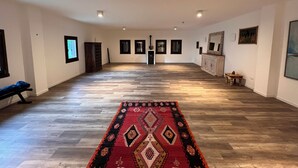 Un'ampia stanza con tappeto decorato, parquet e diverse foto incorniciate alle pareti.