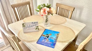 A wooden table with a welcome card, a small vase with flowers, and a travel brochure. - Sunrise at Home by Gloove (El Campello)