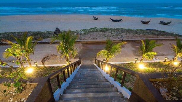 A staircase leading to a beach with boats and palm trees.
