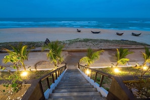A staircase leading to a beach with boats and palm trees.