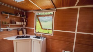 Une cuisine de taille réduite avec des murs en bois, une fenêtre et des étagères intégrées.