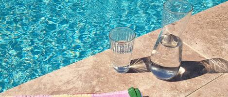 A poolside area with a towel, sunglasses, and glasses.