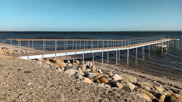Une jetée en bois s’étendant au-dessus d’une côte rocheuse, offrant une vue dégagée sur l’océan.