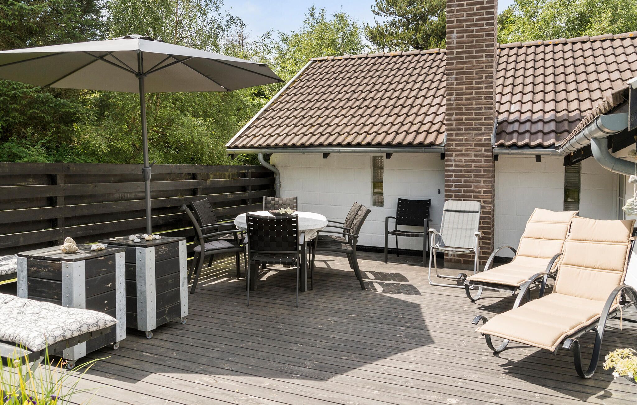 A wooden deck with outdoor furniture, including a table and chairs, and a lounge chair.