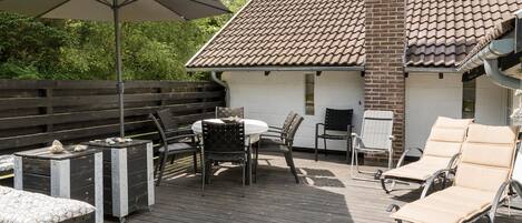 A wooden deck with outdoor furniture, including a table and chairs, and a lounge chair.