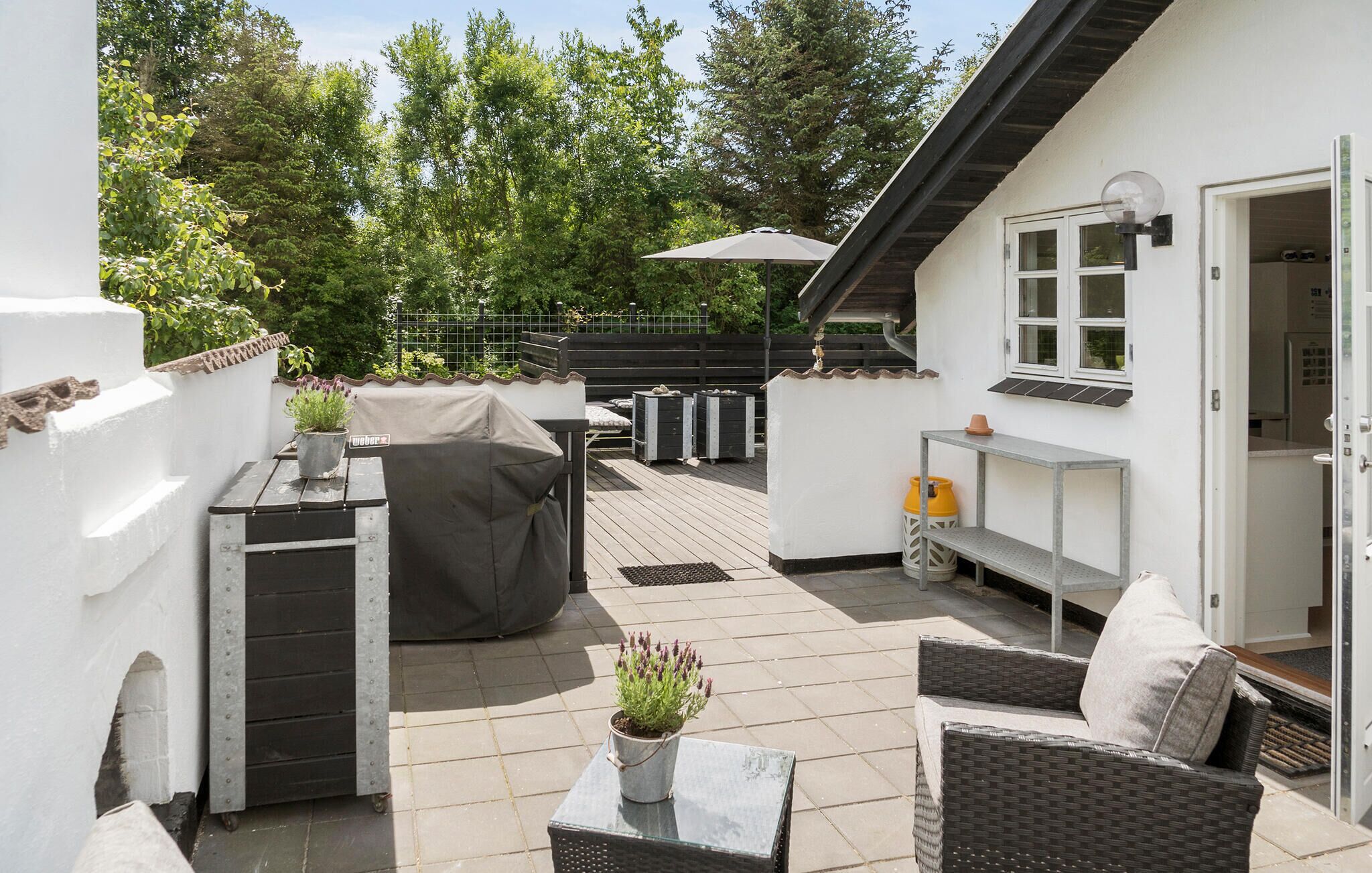 Une terrasse avec des meubles d’extérieur, un barbecue et une plante en pot.