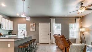 Una cocina moderna con barra, zona de estar con sofá y un ventilador de techo.