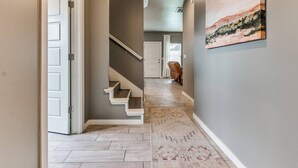 Un pasillo con una escalera, una puerta y un cuadro en la pared.