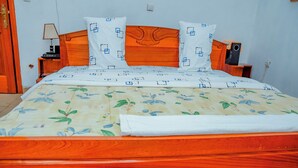 Ein Bett mit floralem Überwurf, einem Holz-Kopfteil und passenden Kissen.