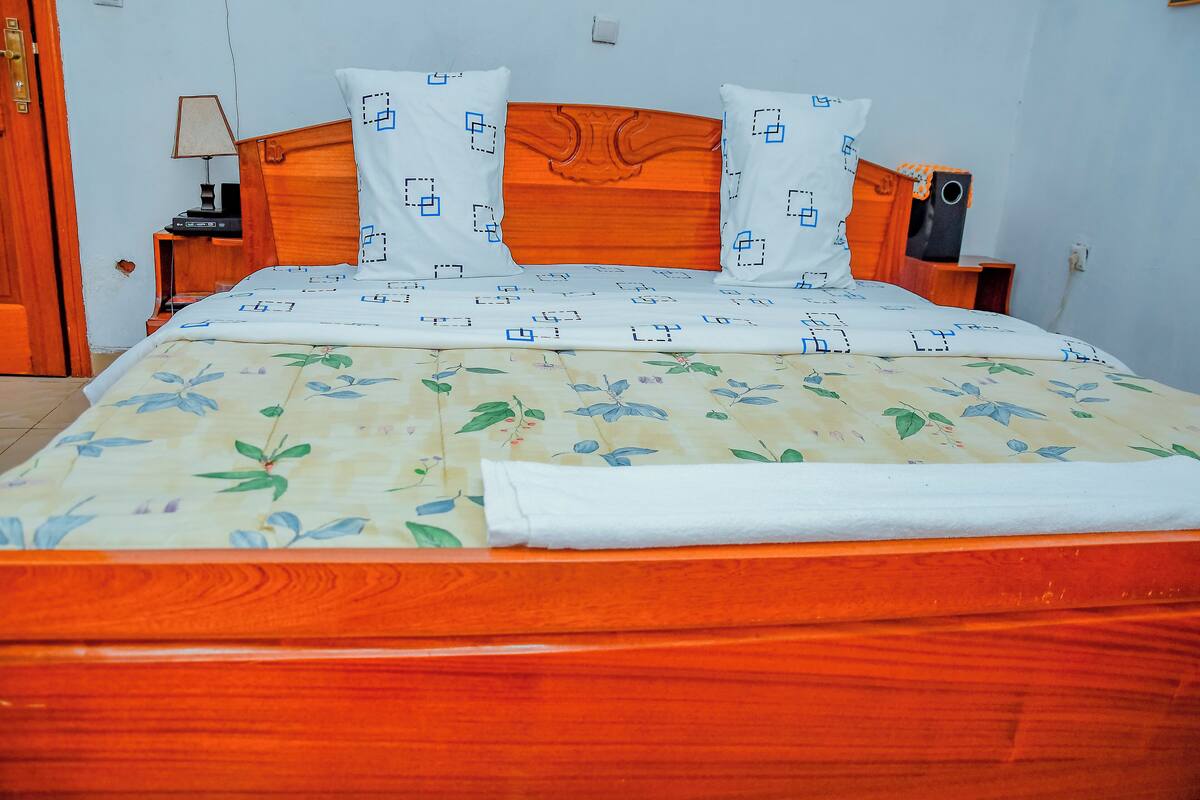 Una cama con cubrecama floral, cabecera de madera y almohadas a juego.