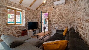 A stone-walled room with a television, sofas, and a wooden table. - Gorgeous home in Vinjerac (Vinjerac)