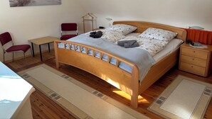 Une chambre à coucher avec un lit en bois, un bureau, une chaise et une table de chevet.