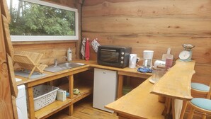 Cocina compacta con encimeras de madera, microondas, refrigerador pequeño y pileta.