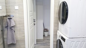 Une buanderie équipée d’un lave-linge et d’un sèche-linge, d’un porte-serviettes et d’une plante en pot.