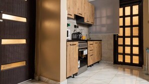 A compact kitchen with wooden cabinets, a built-in oven, and a microwave. - Fed Stay Naalya (Kampala)