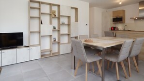 Una cucina moderna con forno a incasso, un'area pranzo con tavolo e sedie e un televisore su un mobile.