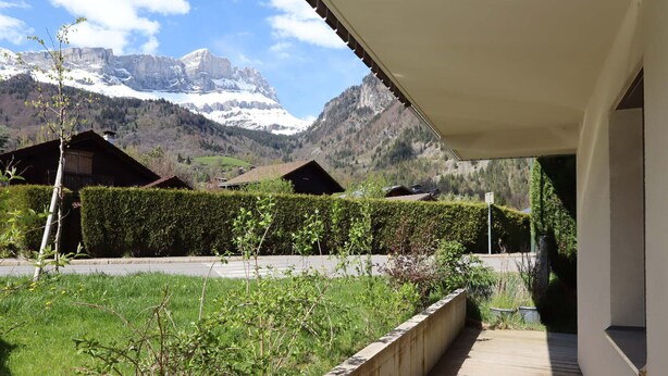 Un pontile di legno conduce a un edificio con vista sulle montagne innevate.