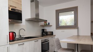 Una cucina moderna con forno, microonde e piano cottura integrati, una finestra con vista e un'area pranzo con tavolo e sedie.