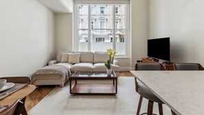 A modern living room with a sofa, coffee table, and TV. - Idyllic Notting Hill 2Bed 2Bath Apartment (London)