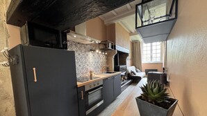 A modern kitchen with a black refrigerator, wooden countertop, and a large potted plant.