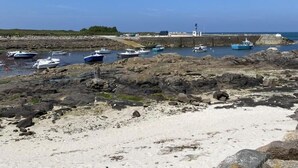 A rocky shoreline with boats docked at a pier.