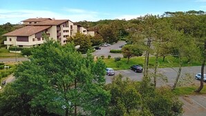 A residential building with multiple balconies, surrounded by greenery and a parking area. - Seaside Retreat: Cozy 1BR Apt Steps from Beach & Shops (Seignosse)