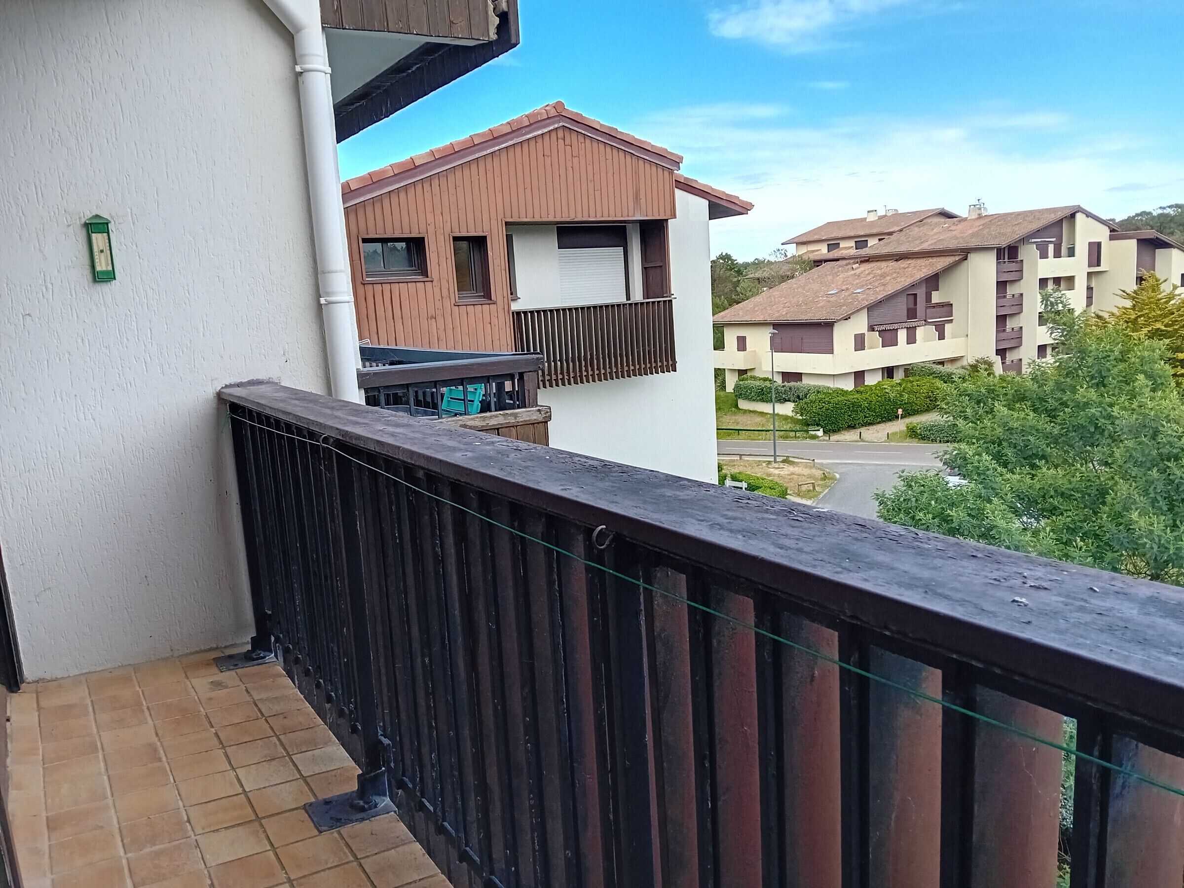 A balcony with a tiled floor and a wooden railing.