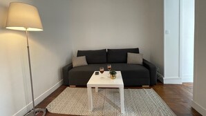 Una sala de estar moderna con un sofá gris oscuro, una mesa de centro blanca y una lámpara de pie.
