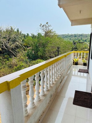 A balcony with a yellow and white balustrade overlooking a lush green landscape. - Ashvem Evaddo (Ashvem)