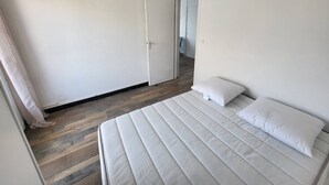 Een slaapkamer met een bed, een deur en een houten vloer.